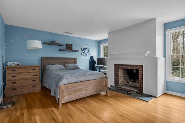 60 Ledgeview Ln, Guilford, CT 06437 - bedroom with wood finished floors, a brick fireplace, and multiple windows