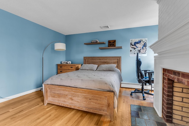 60 Ledgeview Ln, Guilford, CT 06437 - bedroom featuring a brick fireplace, a baseboard heating unit, wood finished floors, and an office area