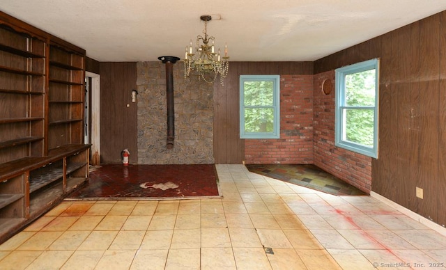 479 Kettletown Rd, Southbury, CT 06488 - unfurnished dining area with a chandelier, a wood stove, and wooden walls