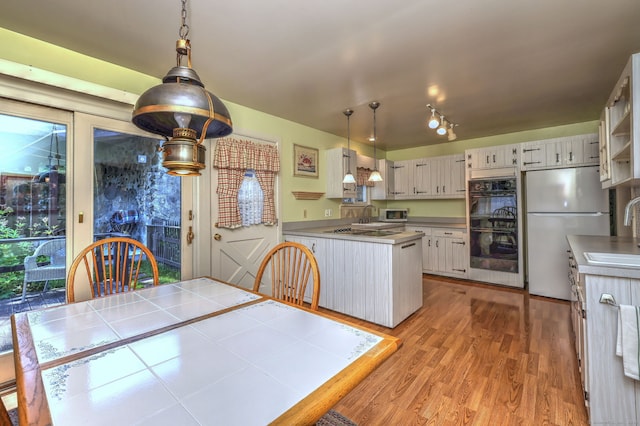21 Oakwood Ave, Waterbury, CT 06708 - kitchen featuring black appliances, light wood-style flooring, a peninsula, hanging light fixtures, and light countertops
