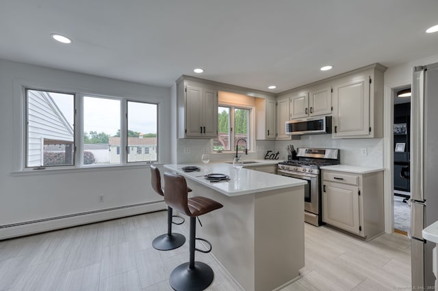 32 Patriot Ln, Newington, CT 06111 - kitchen featuring stainless steel appliances, a baseboard radiator, a peninsula, light countertops, and a kitchen breakfast bar