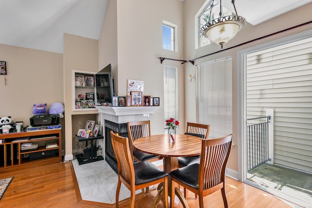 157 Carriage Crossing Ln Unit 157, Middletown, CT 06457 - dining space with a tile fireplace, a towering ceiling, and wood finished floors