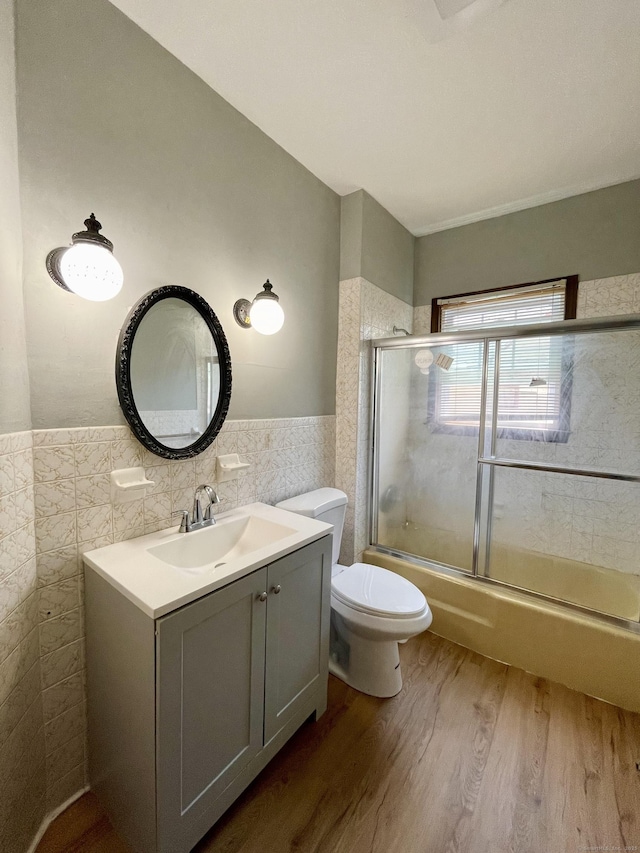 223 S Whitney St, Hartford, CT 06105 - bathroom with tile walls, wood finished floors, bath / shower combo with glass door, vanity, and a wainscoted wall