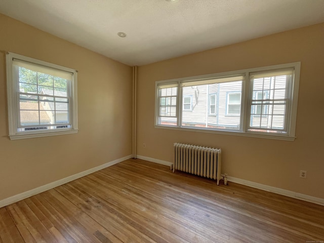 223 S Whitney St, Hartford, CT 06105 - empty room featuring radiator heating unit, plenty of natural light, and wood finished floors