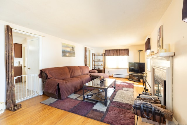 366 Hills St, East Hartford, CT 06118 - living room featuring light wood finished floors, a baseboard heating unit, and a glass covered fireplace