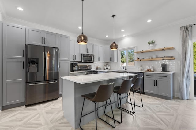 11 Regan Cir, Shelton, CT 06484 - kitchen featuring appliances with stainless steel finishes, gray cabinetry, decorative backsplash, a kitchen island, and a breakfast bar area