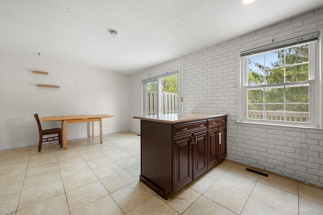 846 Long Hill Rd Unit 846, Middletown, CT 06457 - kitchen featuring light tile patterned flooring, dark brown cabinets, light stone counters, and brick wall