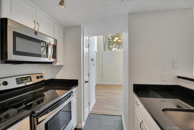 49 Carriage Crossing Ln Unit 49, Middletown, CT 06457 - kitchen featuring stainless steel appliances, white cabinets, a textured ceiling, dark stone countertops, and tile patterned floors