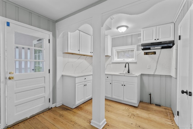 143 Jewett St, Ansonia, CT 06401 - kitchen featuring under cabinet range hood, white cabinetry, light countertops, light wood-style floors, and backsplash