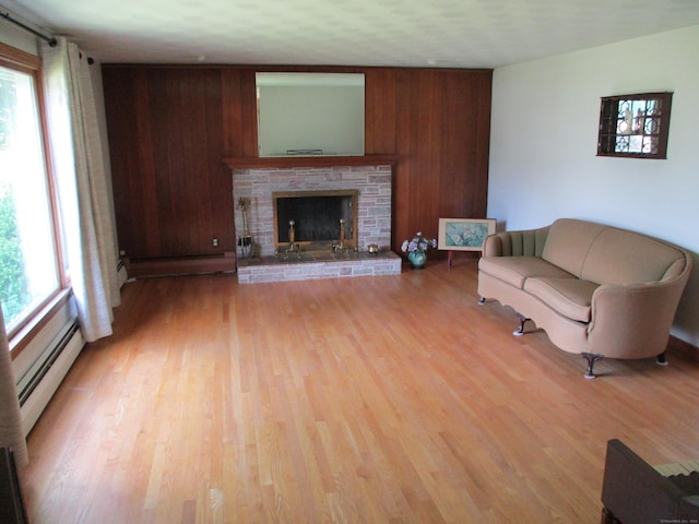 8 Susan Ln, Meriden, CT 06450 - living area featuring a baseboard radiator, light wood finished floors, a stone fireplace, and wooden walls