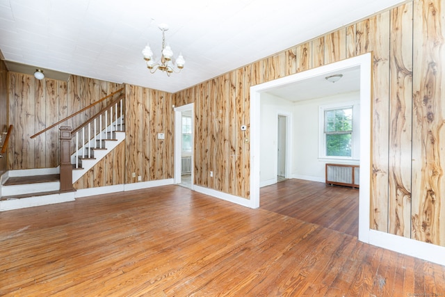 49 Richard Rd, East Hartford, CT 06119 - unfurnished room featuring radiator heating unit, stairway, a chandelier, hardwood / wood-style floors, and wooden walls