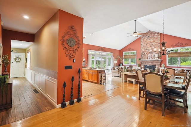 115 Center Rd, Woodstock, CT 06281 - dining room with light wood finished floors, a ceiling fan, a wainscoted wall, a fireplace, and high vaulted ceiling