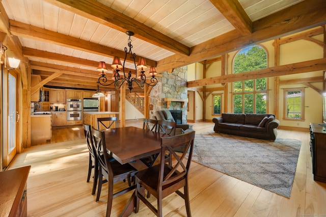 18 Sandpiper Ln, East Lyme, CT 06333 - dining space with light wood-type flooring, a stone fireplace, a chandelier, and a wooden ceiling with exposed beams