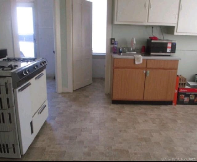 293 Central Ave, Norwich, CT 06360 - kitchen with white range with gas cooktop, stainless steel microwave, light countertops, and white cabinets
