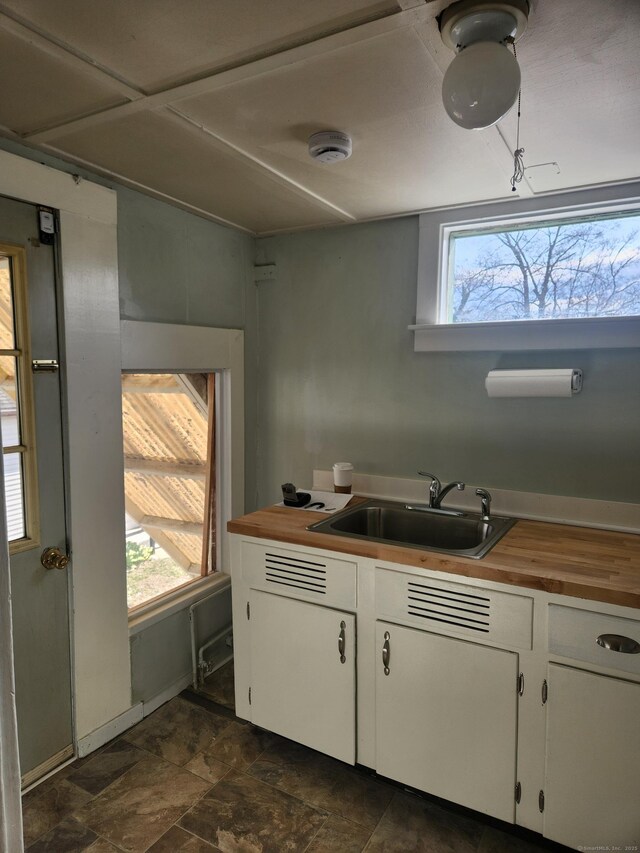 293 Central Ave, Norwich, CT 06360 - kitchen featuring butcher block counters, plenty of natural light, white cabinets, and stone finish floors