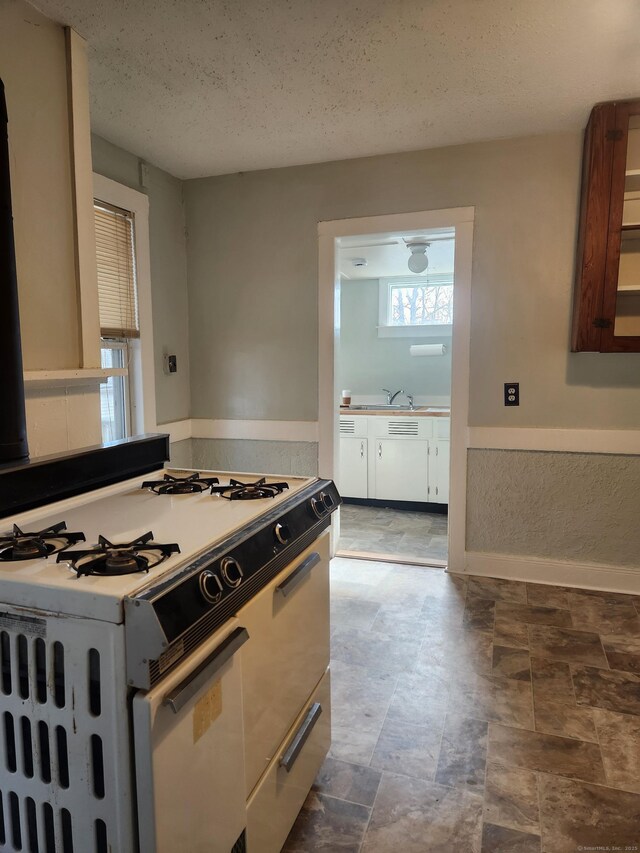 293 Central Ave, Norwich, CT 06360 - kitchen with white gas stove, white cabinetry, a textured ceiling, and light countertops