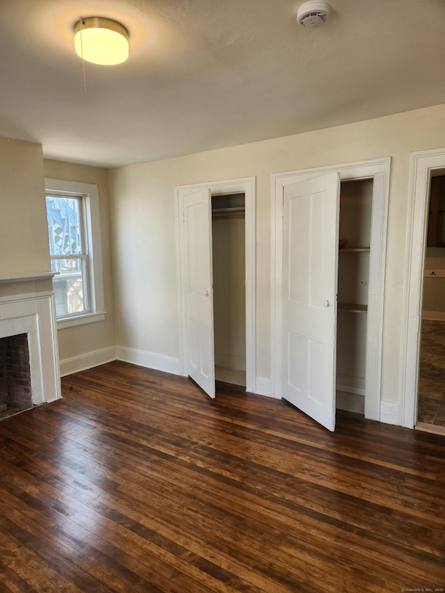 293 Central Ave, Norwich, CT 06360 - unfurnished bedroom with multiple closets, dark wood-style flooring, and a fireplace