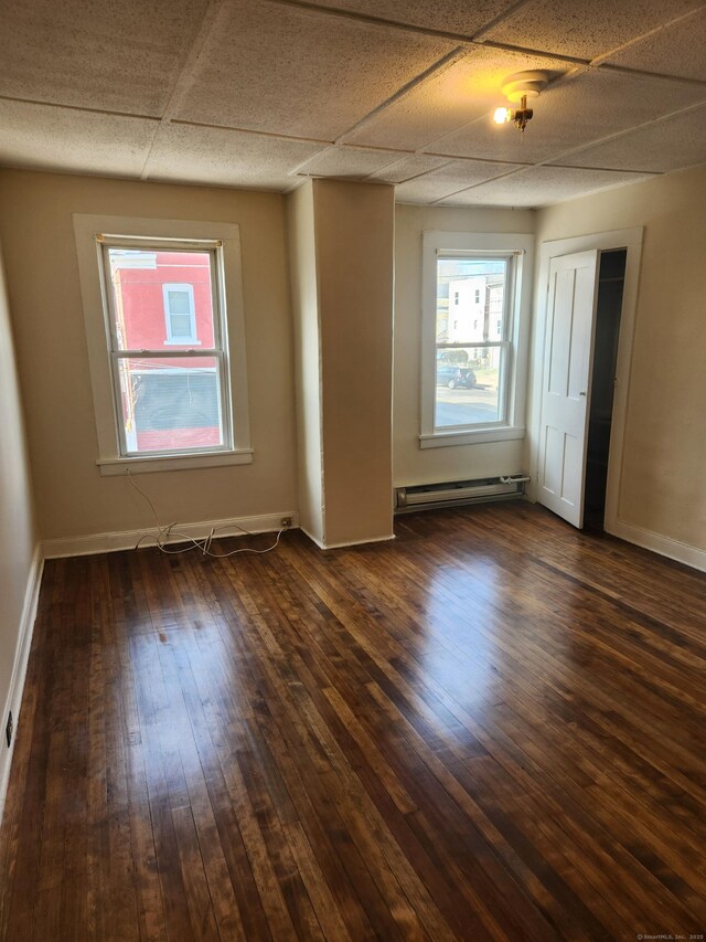 293 Central Ave, Norwich, CT 06360 - unfurnished room featuring a baseboard radiator, dark wood-style floors, and a drop ceiling