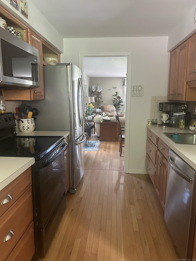 7 Harbour Vlg Unit A, Branford, CT 06405 - kitchen with stainless steel appliances, light countertops, brown cabinets, light wood-style flooring, and tasteful backsplash