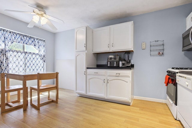 11 Cedar Ct Unit C, East Haven, CT 06513 - kitchen featuring white range with gas cooktop, light wood-style floors, dark countertops, a ceiling fan, and white cabinetry