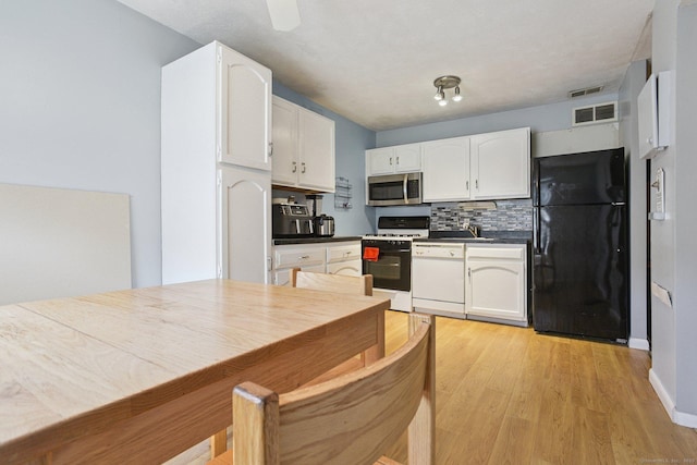 11 Cedar Ct Unit C, East Haven, CT 06513 - kitchen featuring white appliances, white cabinets, backsplash, dark countertops, and light wood-type flooring