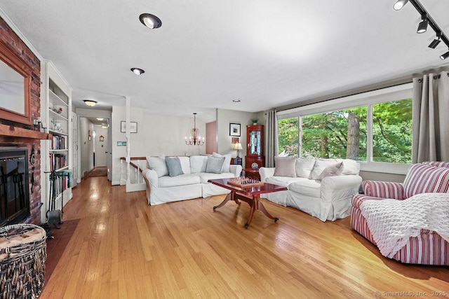 18 Chestnut Hill Rd, Simsbury, CT 06092 - living room featuring a chandelier, built in features, light wood-type flooring, track lighting, and a brick fireplace