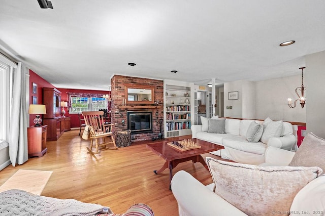 18 Chestnut Hill Rd, Simsbury, CT 06092 - living room featuring light wood finished floors, a chandelier, a brick fireplace, built in shelves, and recessed lighting