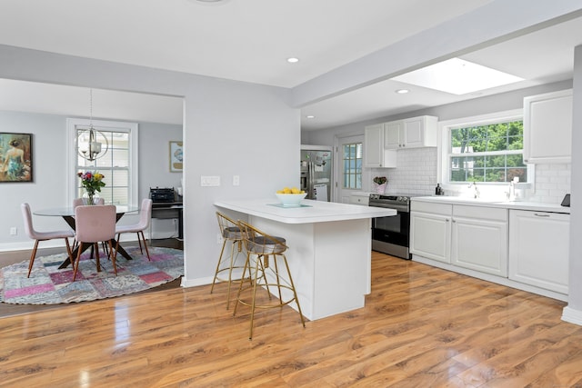 11 Margaret St, Norwalk, CT 06851 - kitchen with stainless steel appliances, white cabinetry, a breakfast bar area, decorative backsplash, and a peninsula