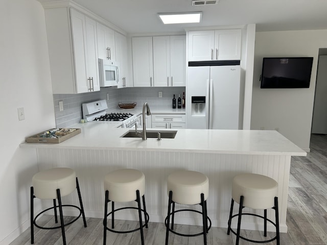 63 E Broadway Unit D, Milford, CT 06460 - kitchen with white appliances, a peninsula, light wood finished floors, light countertops, and decorative backsplash