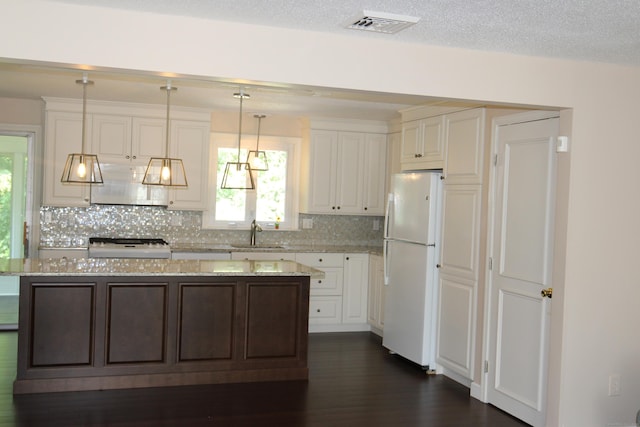 2337 Stanley St, New Britain, CT 06053 - kitchen with freestanding refrigerator, range hood, decorative backsplash, a center island, and light stone countertops
