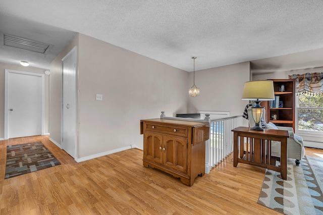 315 Judson Ave, Groton, CT 06355 - kitchen featuring brown cabinetry, light wood finished floors, a textured ceiling, and pendant lighting
