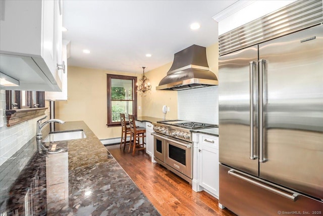 1384 N Benson Rd, Fairfield, CT 06824 - kitchen featuring premium appliances, wall chimney exhaust hood, white cabinetry, dark stone countertops, and backsplash