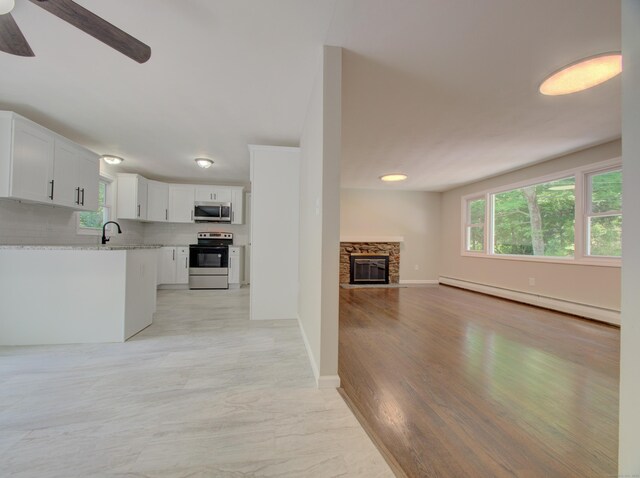185 Hope Valley Rd, Hebron, CT 06231 - unfurnished living room with a baseboard heating unit, ceiling fan, and a stone fireplace