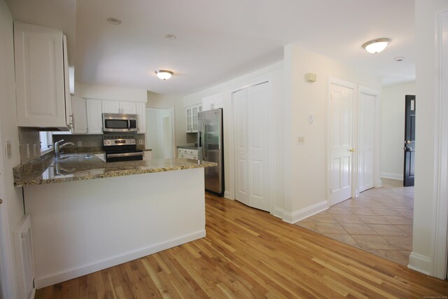 1 Quaker Ridge Rd, Sherman, CT 06784 - kitchen featuring appliances with stainless steel finishes, a peninsula, stone counters, white cabinets, and light wood-type flooring