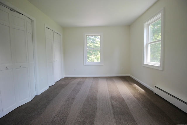 1 Quaker Ridge Rd, Sherman, CT 06784 - unfurnished bedroom with a baseboard radiator, two closets, and dark carpet