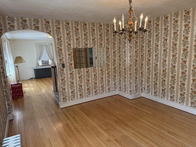 28 Maplerow Ave, Waterbury, CT 06705 - unfurnished dining area with radiator heating unit, wood finished floors, a chandelier, arched walkways, and wallpapered walls
