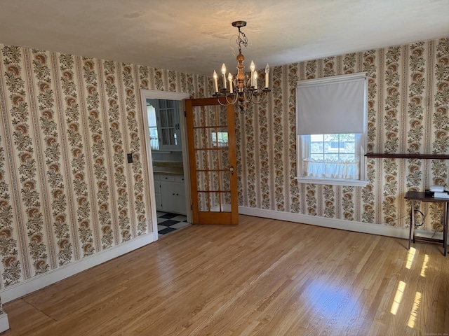 28 Maplerow Ave, Waterbury, CT 06705 - empty room featuring wallpapered walls, wood finished floors, and a chandelier