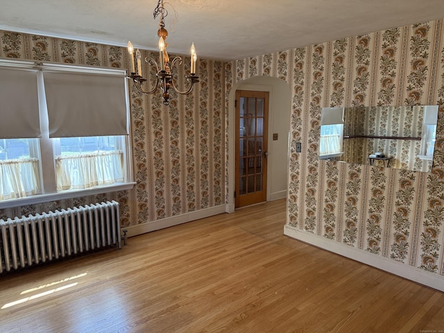 28 Maplerow Ave, Waterbury, CT 06705 - spare room featuring radiator heating unit, arched walkways, wood finished floors, wallpapered walls, and a chandelier