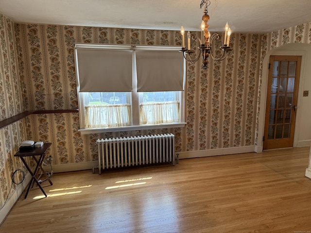 28 Maplerow Ave, Waterbury, CT 06705 - unfurnished dining area with radiator heating unit, wood finished floors, arched walkways, a chandelier, and wallpapered walls