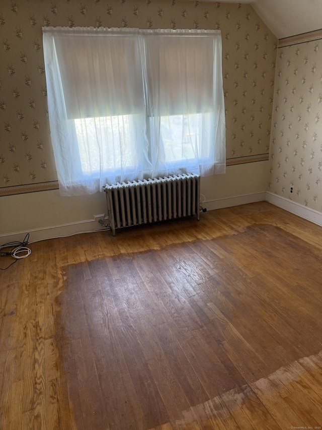 28 Maplerow Ave, Waterbury, CT 06705 - additional living space featuring radiator heating unit, plenty of natural light, wallpapered walls, and wood finished floors