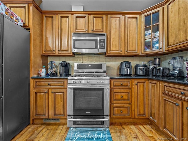 126 Conrad Dr, New Haven, CT 06515 - kitchen featuring appliances with stainless steel finishes, brown cabinetry, light wood-type flooring, and decorative backsplash
