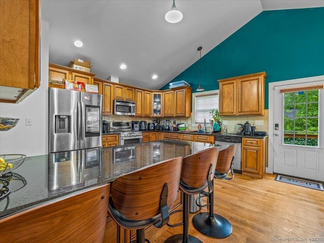 126 Conrad Dr, New Haven, CT 06515 - kitchen with appliances with stainless steel finishes, brown cabinetry, backsplash, a kitchen breakfast bar, and high vaulted ceiling