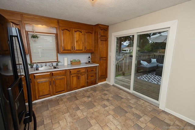 18 Hull Dr, Southington, CT 06479 - kitchen featuring light countertops, brown cabinets, a textured ceiling, dark stone finish floors, and freestanding refrigerator