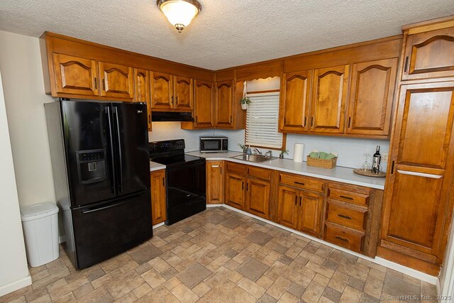 18 Hull Dr, Southington, CT 06479 - kitchen featuring black appliances, under cabinet range hood, light countertops, brown cabinetry, and a textured ceiling