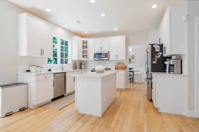 81 Salem Rd, Trumbull, CT 06611 - kitchen with stainless steel appliances, a kitchen island, tasteful backsplash, white cabinetry, and light wood finished floors
