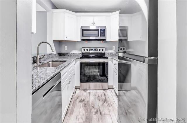 175 Mill Pond Rd Unit 203, Hamden, CT 06514 - kitchen with appliances with stainless steel finishes, light stone countertops, white cabinetry, and light wood finished floors