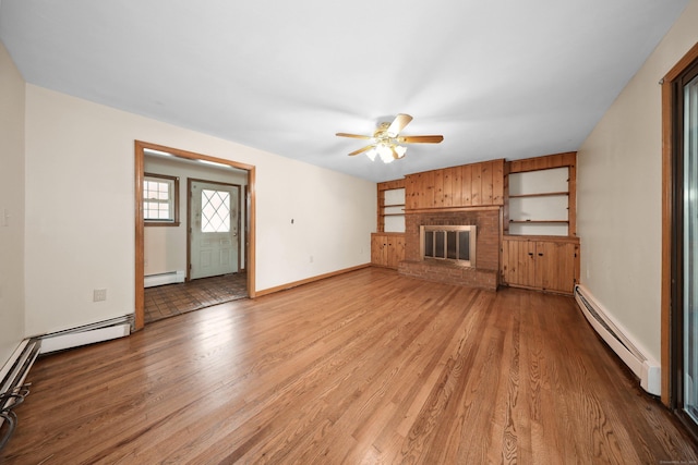 120 Knowles Ave, Southington, CT 06479 - unfurnished living room featuring a baseboard radiator, light wood finished floors, a ceiling fan, a fireplace, and wooden walls