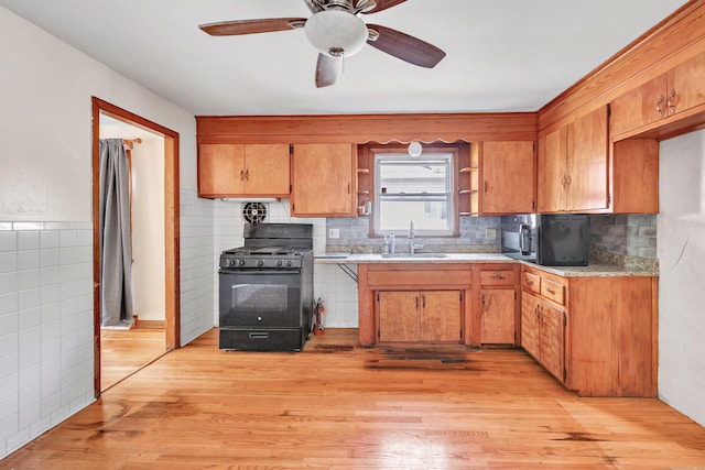 70 Sage Ave, Bridgeport, CT 06610 - kitchen featuring black range with gas stovetop, tile walls, light wood-style flooring, a ceiling fan, and brown cabinetry