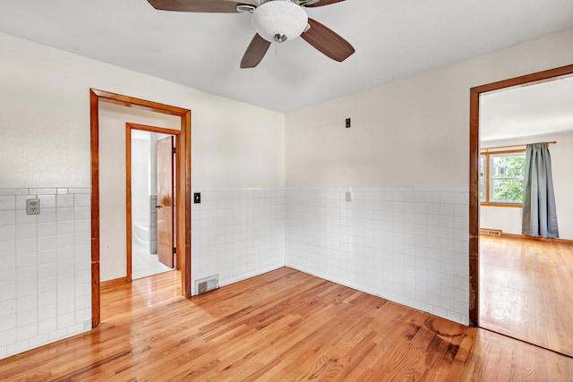 70 Sage Ave, Bridgeport, CT 06610 - empty room with tile walls, light wood-type flooring, a wainscoted wall, and ceiling fan