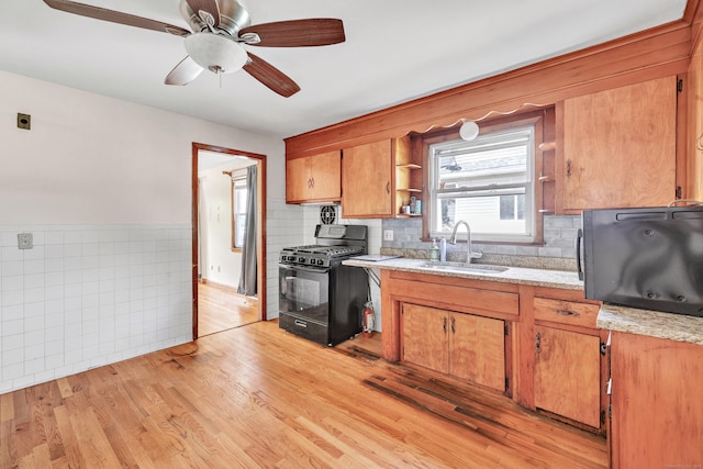70 Sage Ave, Bridgeport, CT 06610 - kitchen with black gas range oven, open shelves, brown cabinets, a ceiling fan, and light wood-style floors